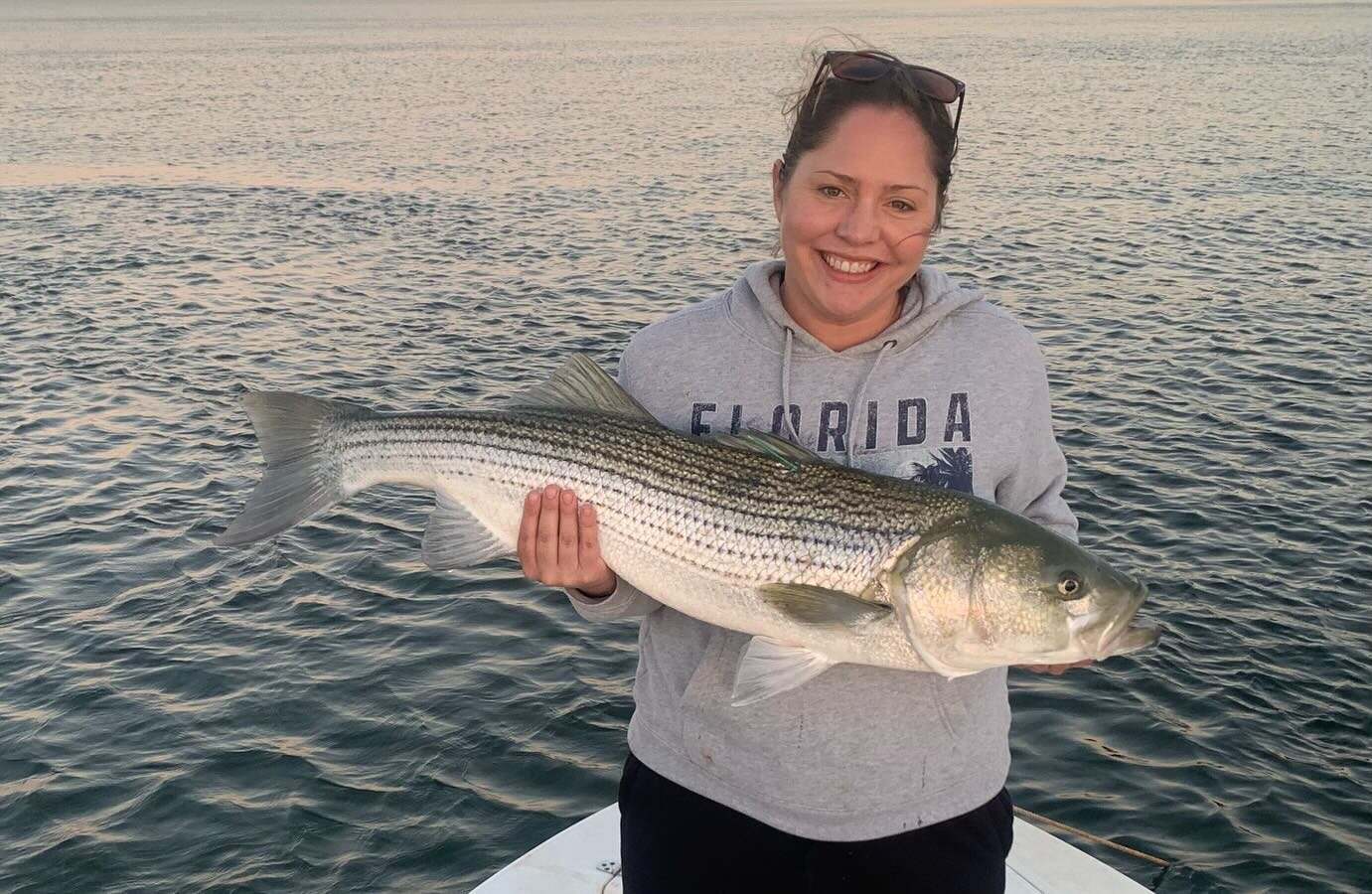 Angler holding a trophy striped bass at sunset