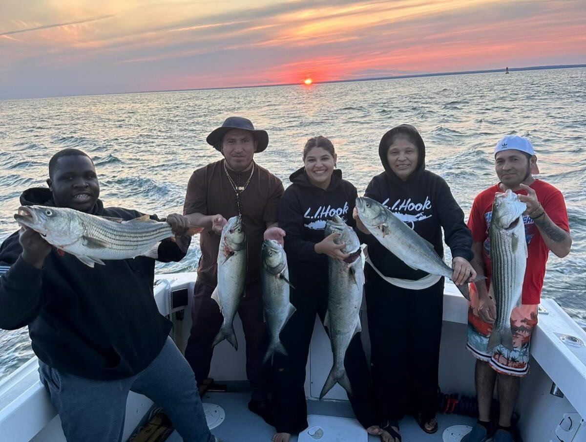 Group on board with mixed catch under a red sunset
